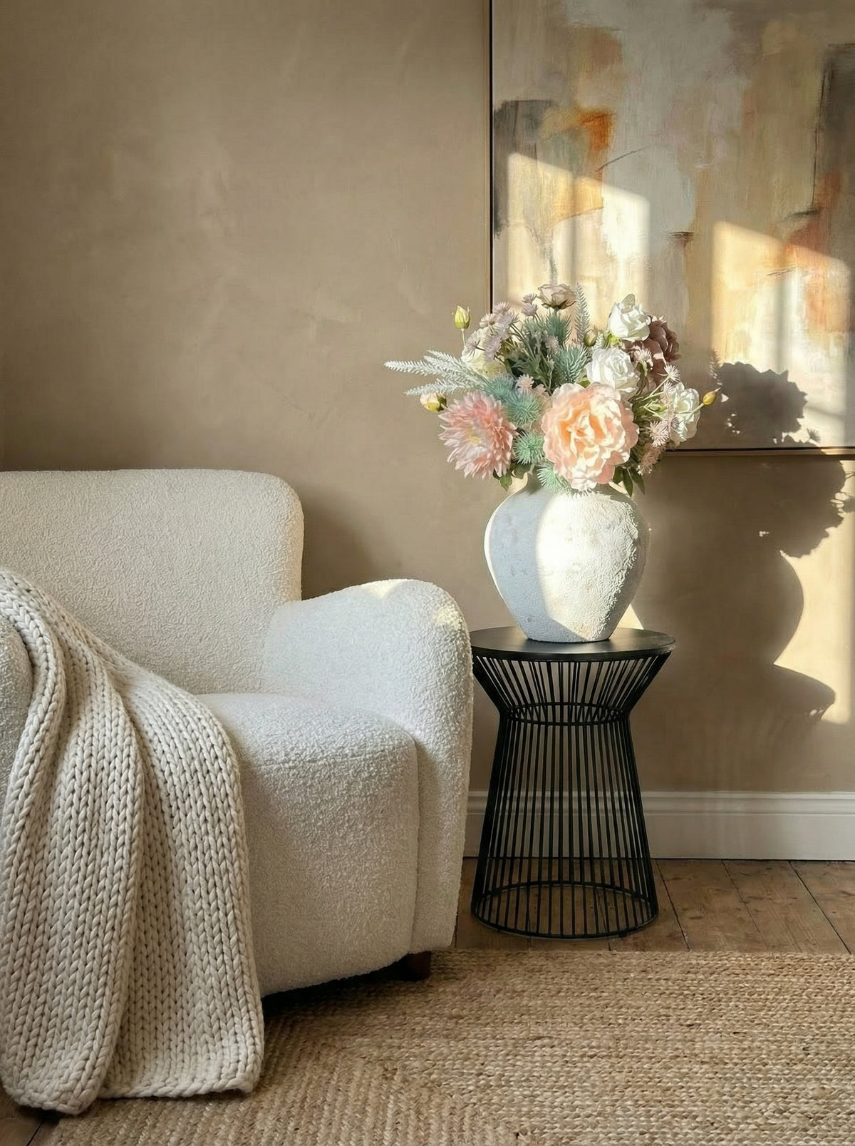 Cozy living room with a white armchair, floral arrangement, and abstract painting.