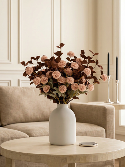Bouquet of pink flowers in a white vase on a coffee table in a living room.
