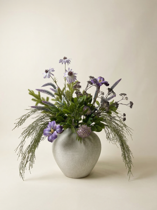Decorative flower arrangement in a textured vase on a light background