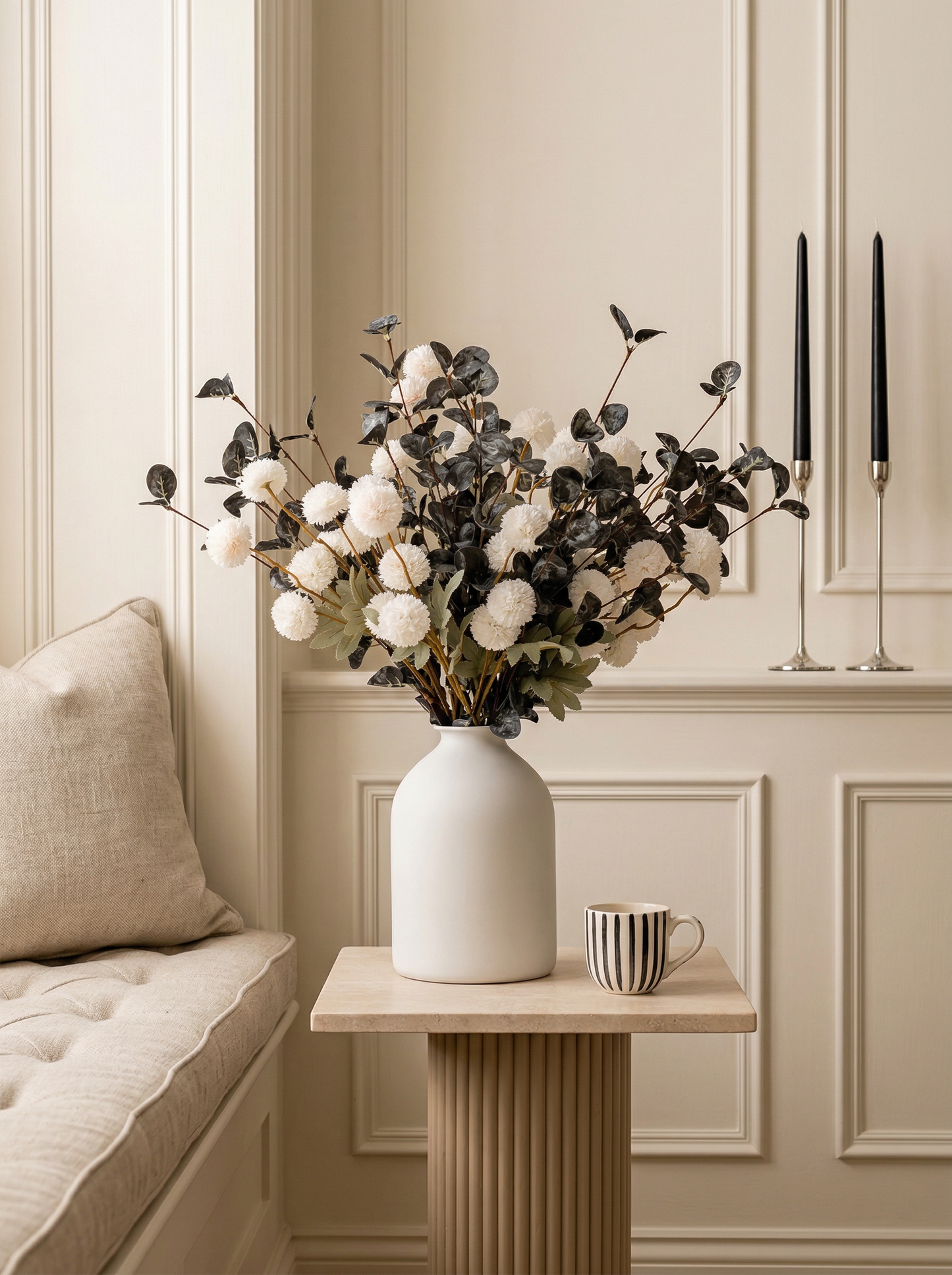 Decorative vase with flowers on a small table in a room with a couch and wall art.