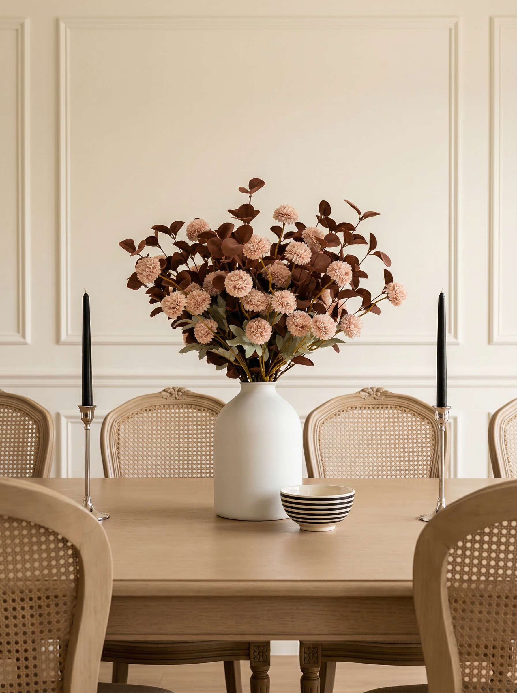 Dining room table with a vase of flowers and candles on a neutral background