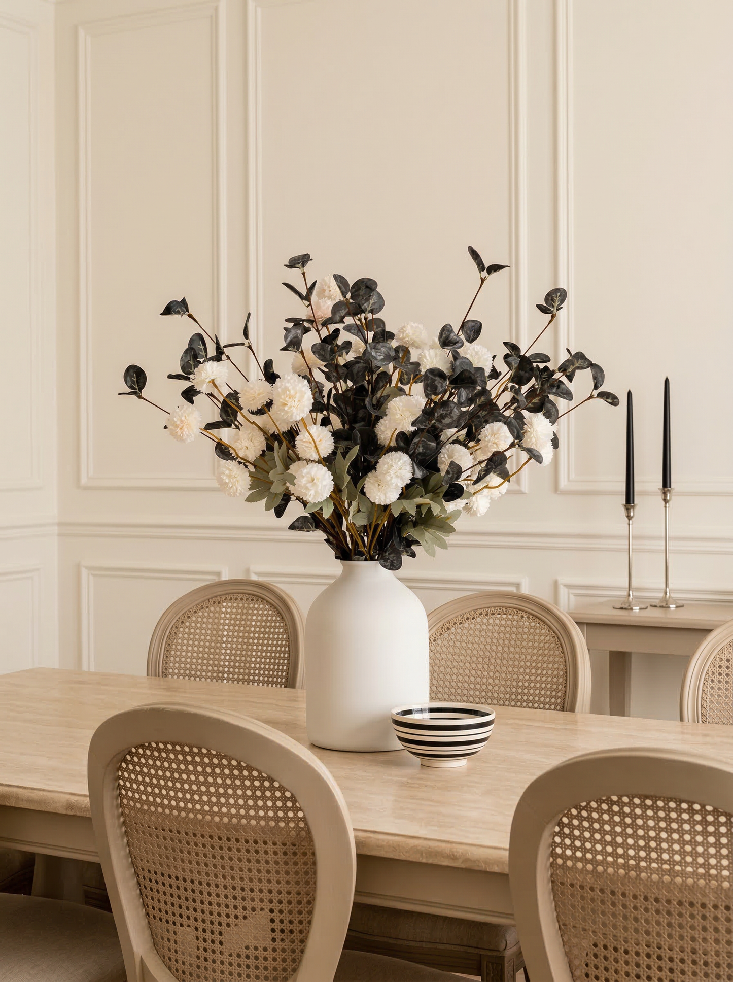 Dining room with a table, chairs, and a vase with flowers on a neutral background
