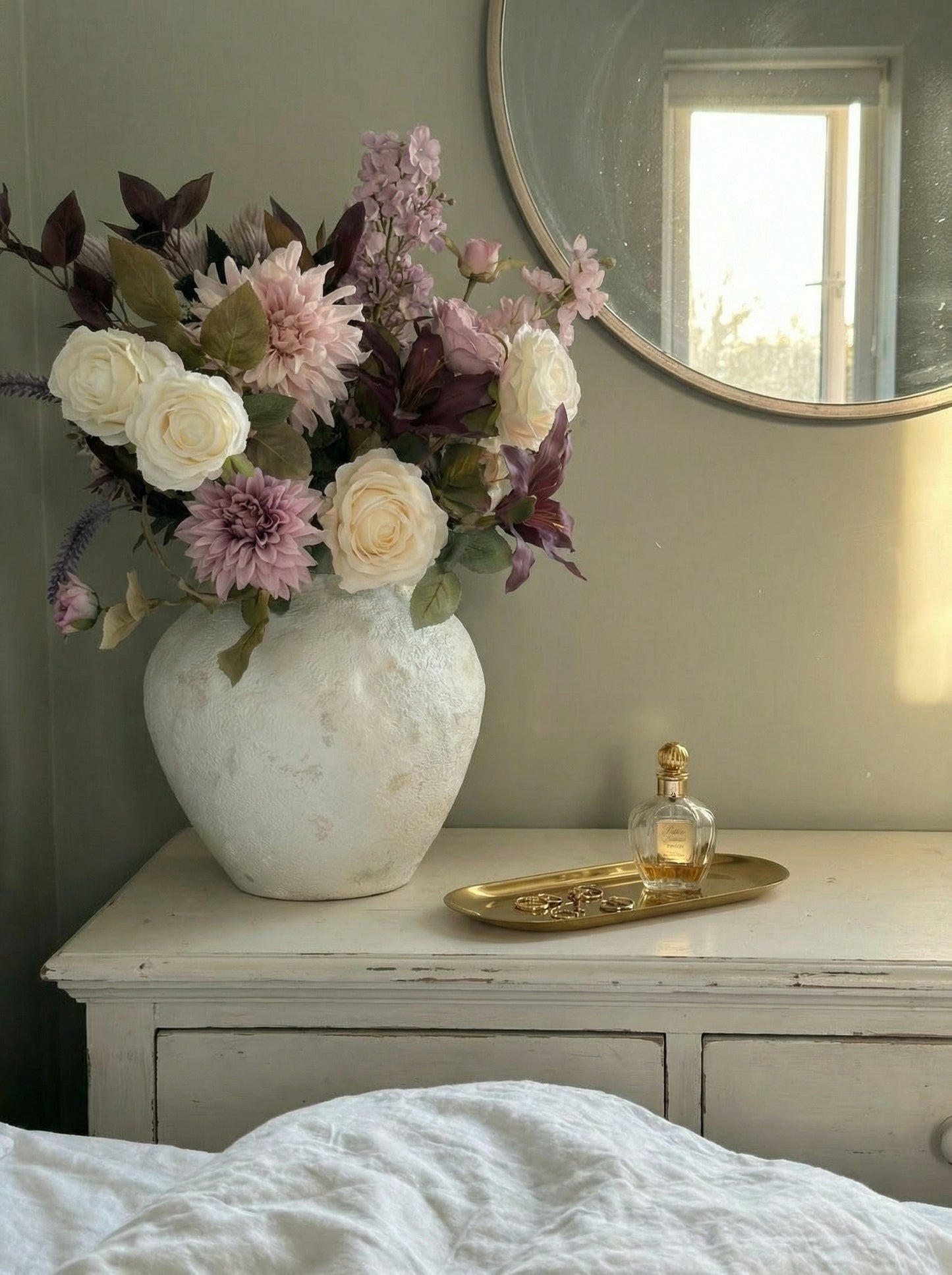 Floral arrangement in a vase on a dresser with a mirror in the background