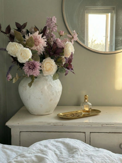 Floral arrangement in a vase on a dresser with a mirror in the background