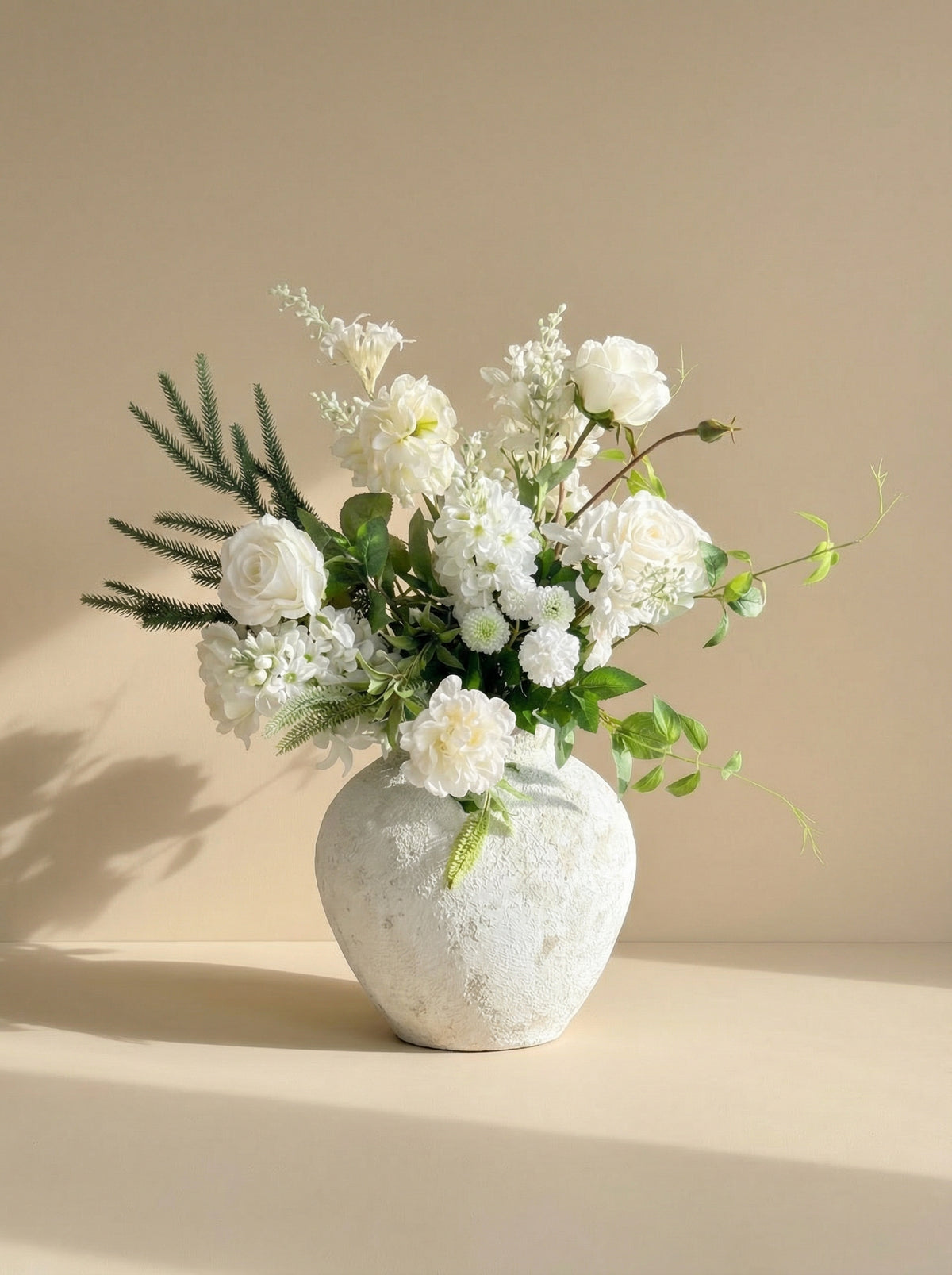White floral arrangement in a textured white vase on a beige background