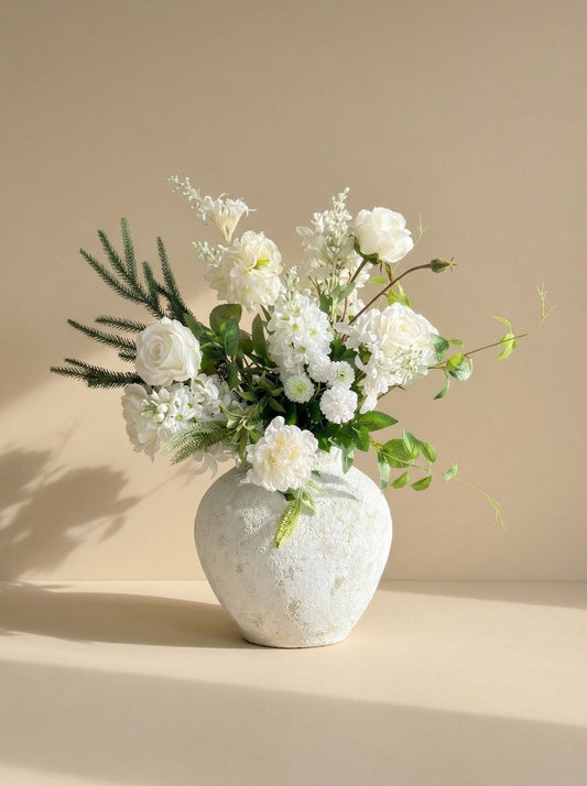 White floral arrangement in a textured white vase on a beige background