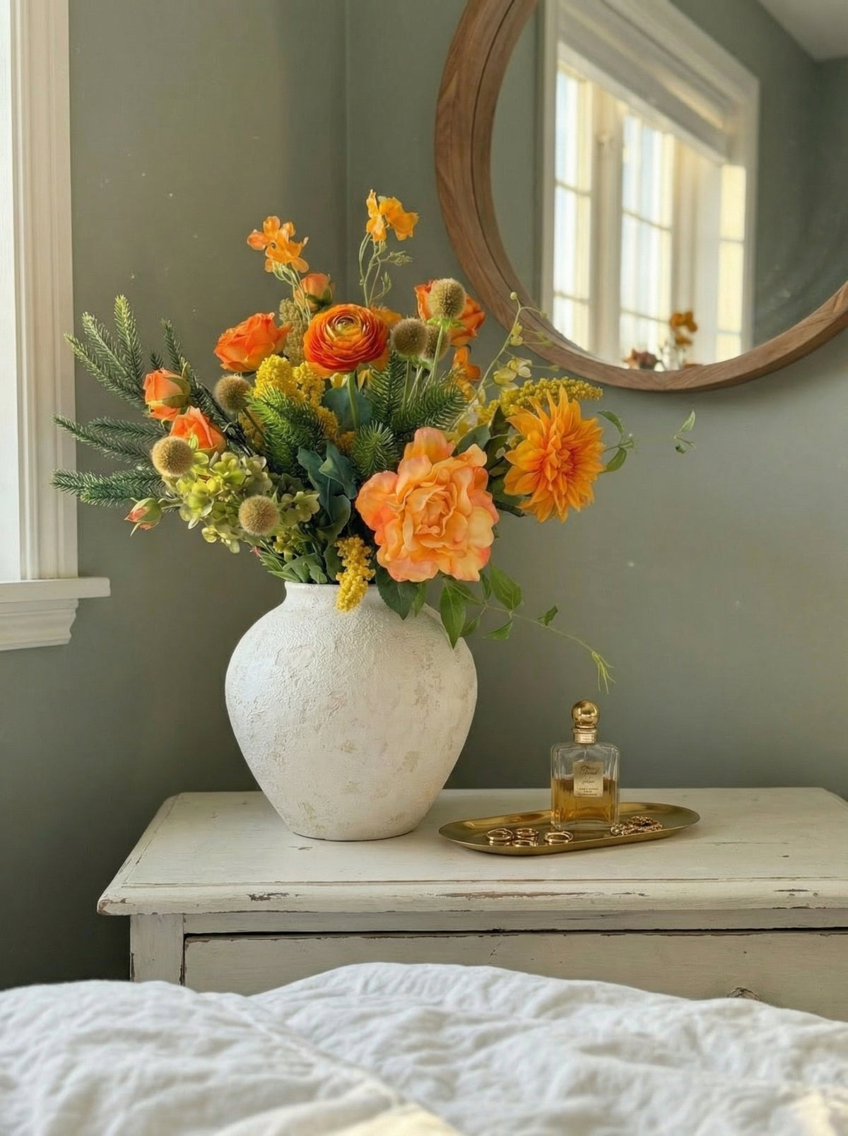White vase with orange and yellow flowers on a wooden nightstand against a gray wall.
